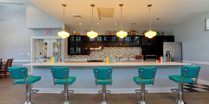 A bar with green chairs and a white counter. at Rainier Manor Apartments, Maryland, 20712