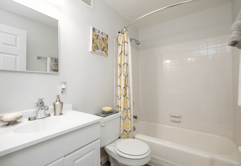 A white bathroom with a toilet, sink, and shower.