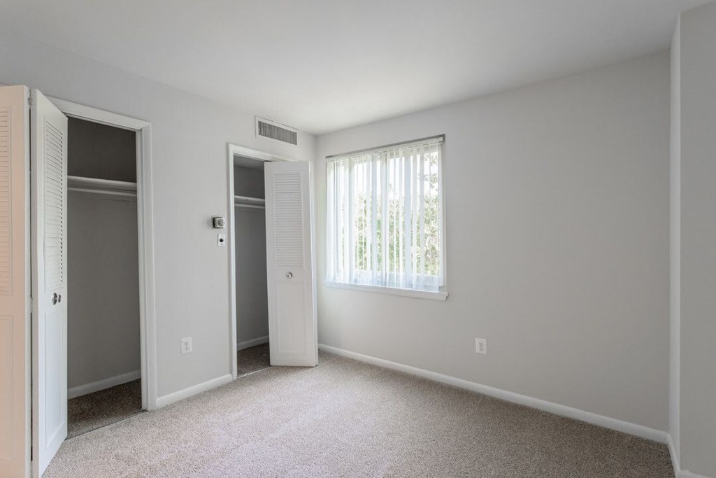 A white bedroom with a window and a carpeted floor. A white bedroom with a window and a carpeted floor at Charlestowne North Apartments, Greenbelt