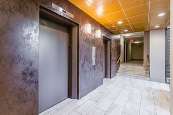 A hallway with a brown wall and a white tiled floor.