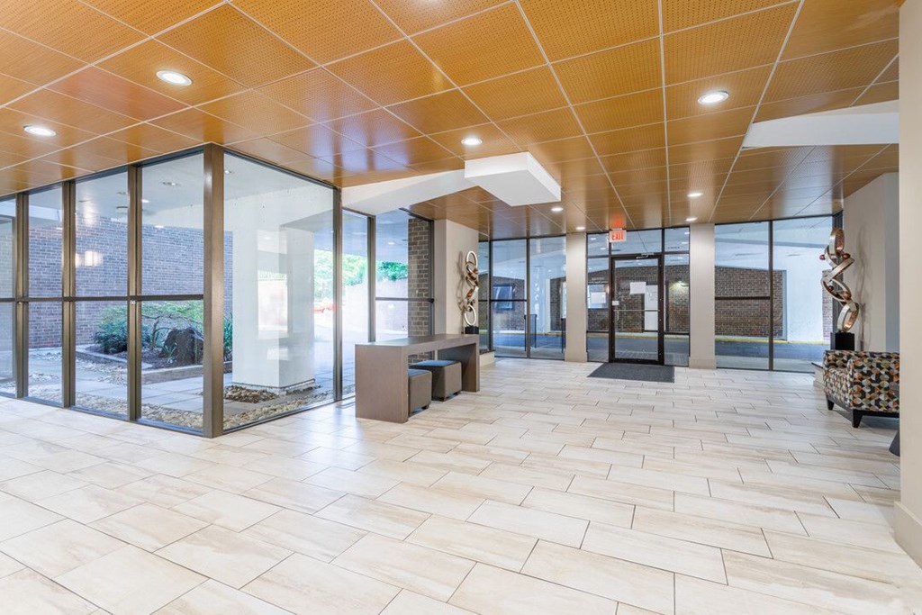 A spacious hallway with a tiled floor and glass walls leading to an outdoor area. A spacious hallway with a tiled floor and glass walls leading to an outdoor area at Charlestowne North Apartments, Greenbelt, MD