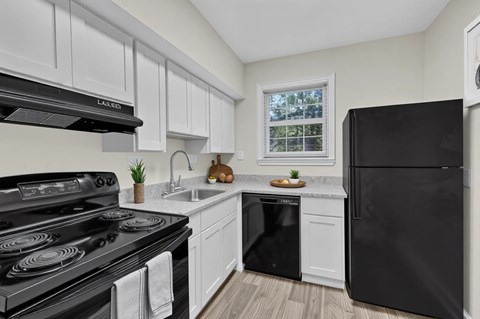 A black stove top oven sits in a kitchen with white cabinets.