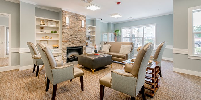 A living room with a fireplace and grey chairs. at Rainier Manor Apartments, Maryland