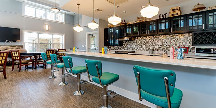 A kitchen with a bar area and green chairs at Rainier Manor Apartments, Maryland