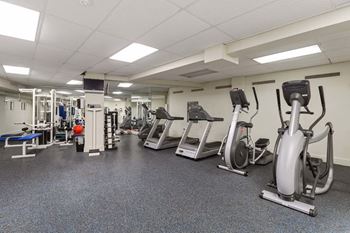 A gym with a variety of exercise equipment including treadmills, stationary bikes, and weight machines.