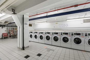 A row of washing machines are lined up in a laundromat.