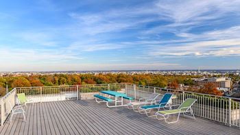 A wooden deck with four chairs and a table overlooking a cityscape.
