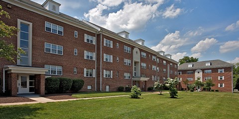A large red brick building with a green lawn in front. at University Landing Apartments, Silver Spring, MD