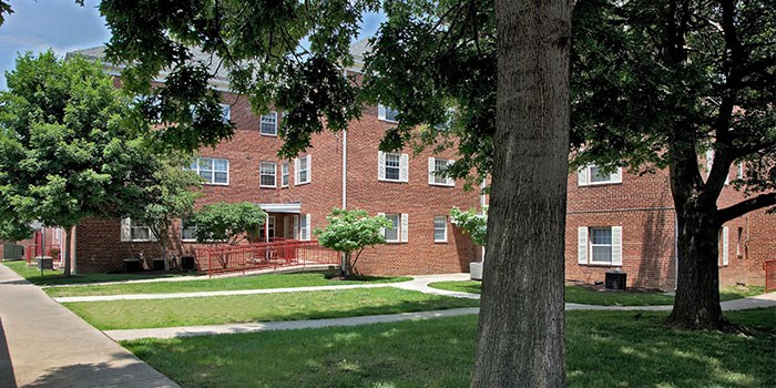 A tree is in the foreground of a brick building. at University Landing Apartments, Maryland, 20903