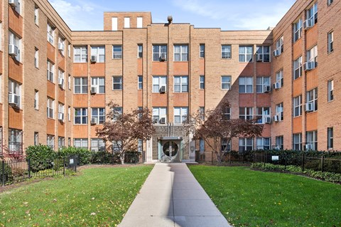 A long brick building with a walkway in front.