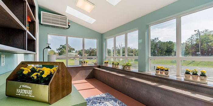 A sunny room with a long window and a wooden box of flowers on the table. at Rainier Manor Apartments, Mount Rainier, MD, 20712