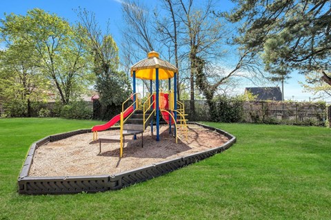 A playground with a yellow and red slide and a yellow and blue tower.