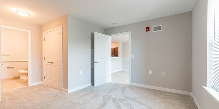 A room with a carpeted floor and a fire extinguisher on the wall. at Rainier Manor Apartments, Mount Rainier, MD