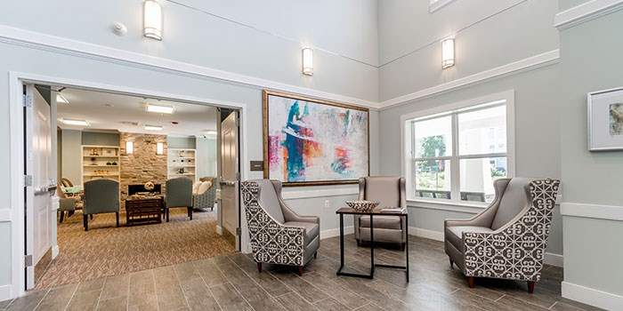 A living room with a large painting on the wall and a view of a kitchen through the open door at Rainier Manor Apartments, Maryland, 20712