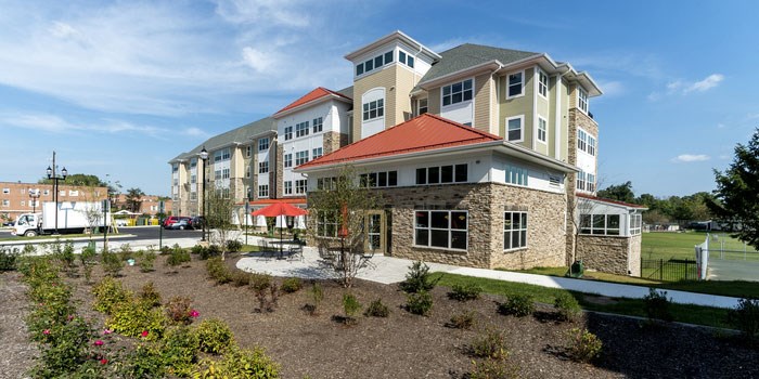 A large building with a red roof and stone pillars at Rainier Manor Apartments, Mount Rainier