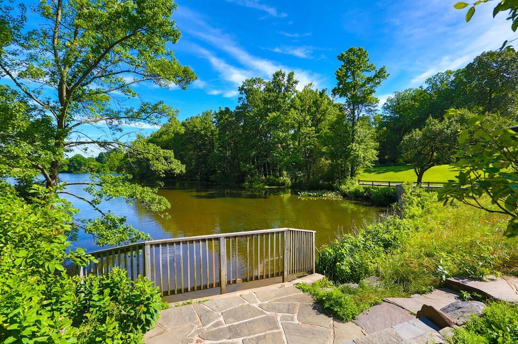 A serene park with a lake, trees, and a stone walkway at Charlestowne North Apartments, Greenbelt, MD