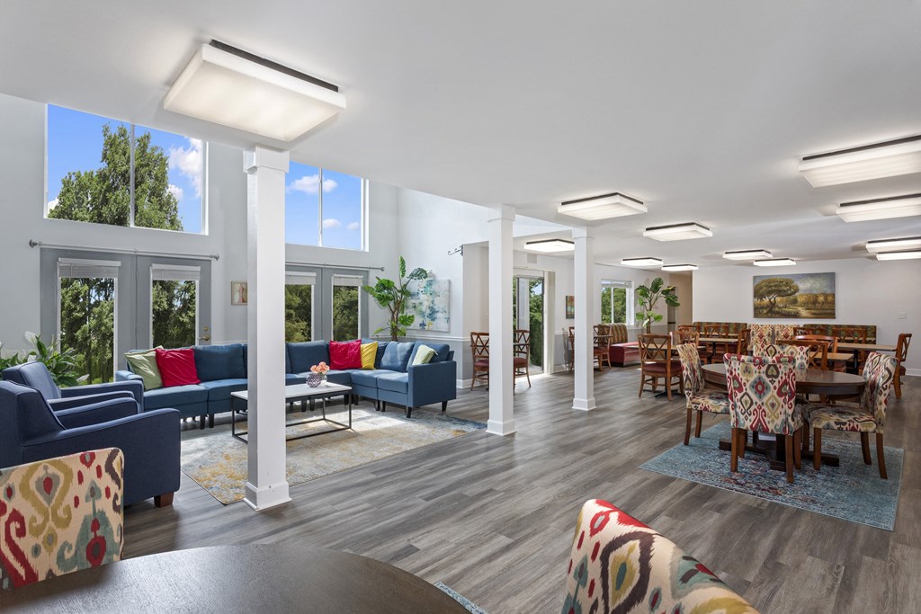 community space at Creekside at Taskers Chance in Frederick, MD with blue couches and chairs, and scattered dining tables with four chairs each