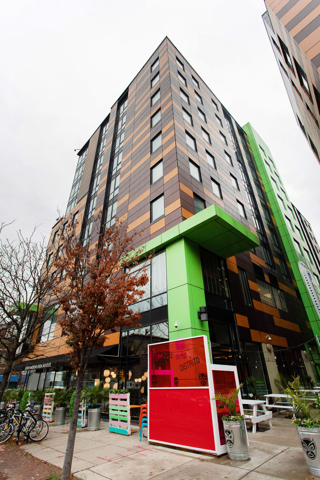 a tall building with a green and orange facade and a red door