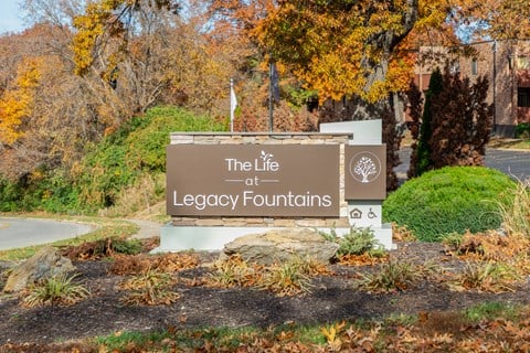 A sign that says "The Life at Legacy Fountains" is in front of a building.