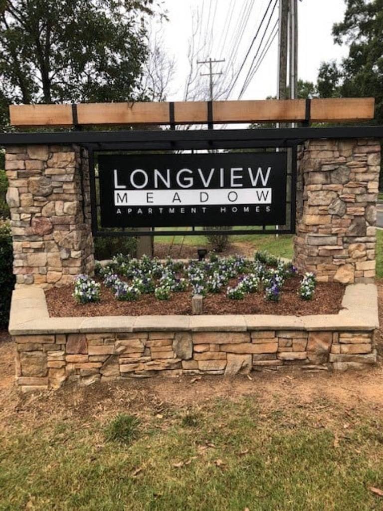 a sign for longview mega town in front of a stone wall with a garden