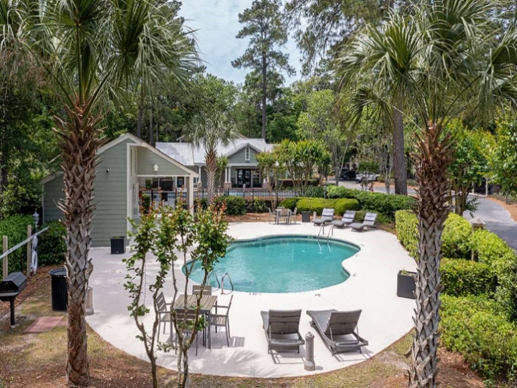 a pool is surrounded by chairs and palm trees