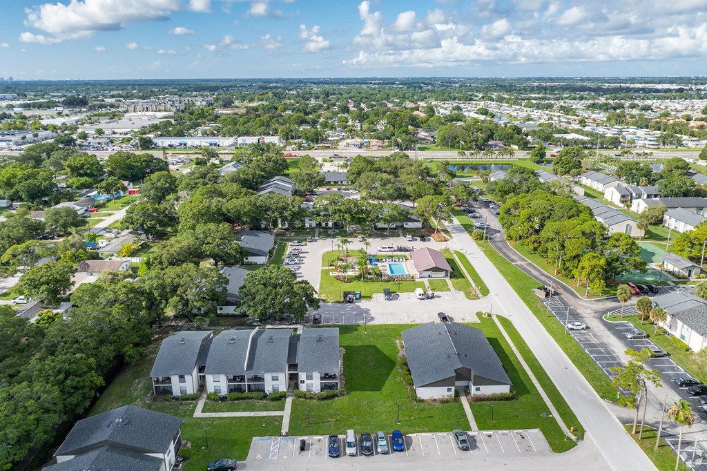 A bird's eye view of a residential area with houses, trees, and a parking lot.