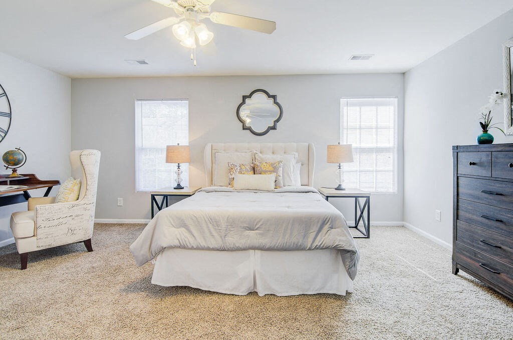 a bedroom with a bed and two windows at Enclave at West Ashley Apartments, Charleston, SC, 29414