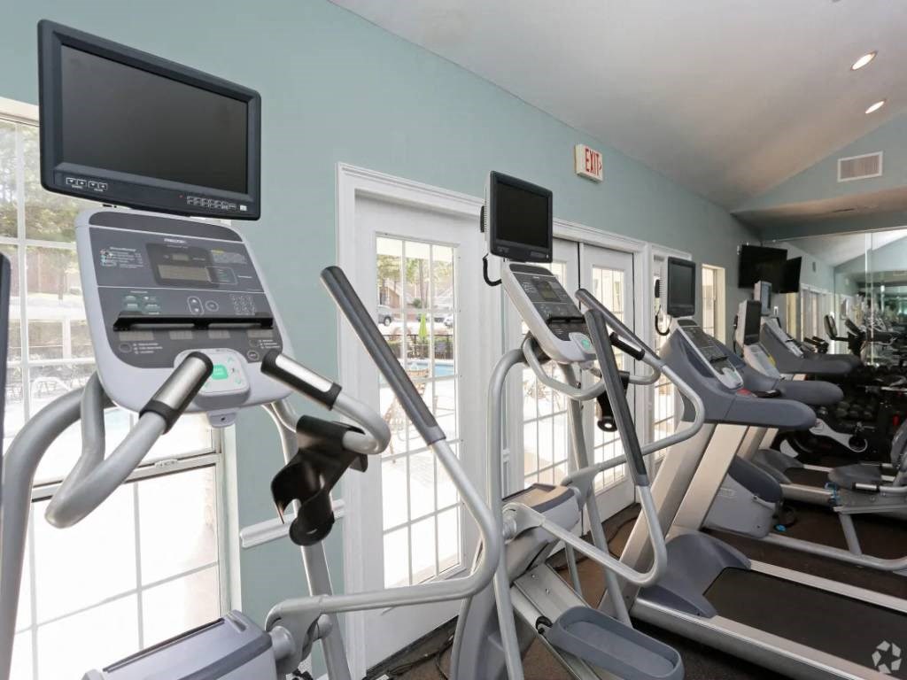 a gym with cardio equipment and a tv