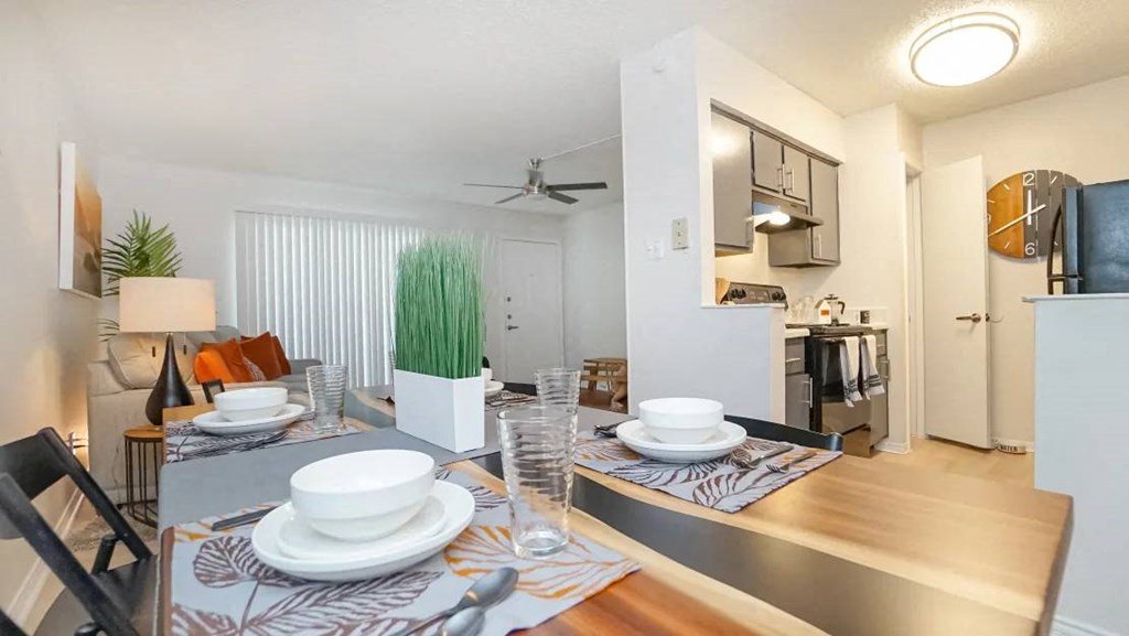 a dining room with a table and a kitchen in the background at Elevate at Huebner Grove, San Antonio, TX 78230
