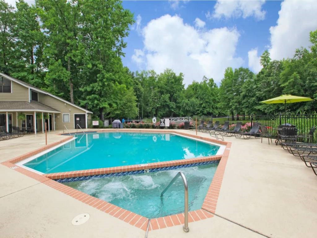 a resort style pool with chairs and umbrellas next to a house