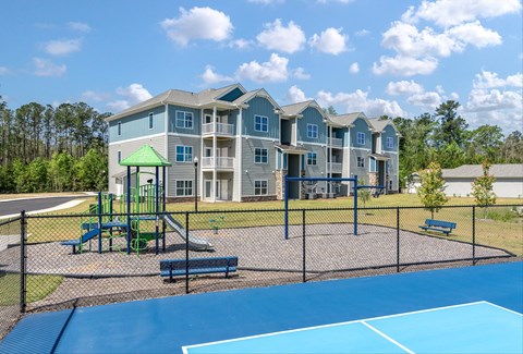 A large apartment complex with a playground and tennis court.