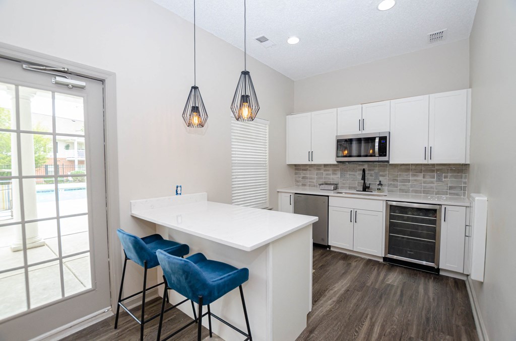 a kitchen with white cabinets and a white counter top and blue chairs