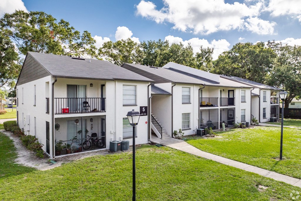 Apartment complex with white buildings and green grass.