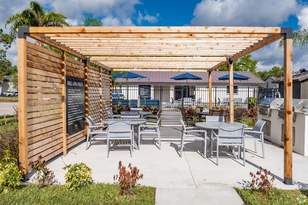A wooden pergola with a sign and chairs under it.