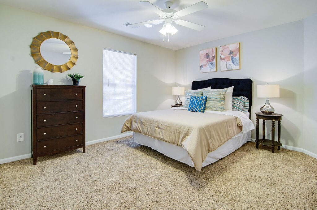 a bedroom with a ceiling fan and a dresser at Enclave at West Ashley Apartments, Charleston,SC