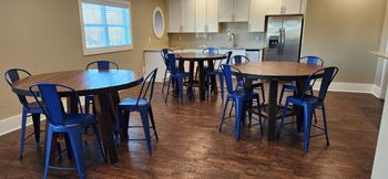 a dining room with tables and chairs and a kitchen