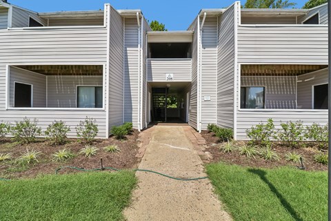 A concrete pathway leads to a building with a hose on the ground.