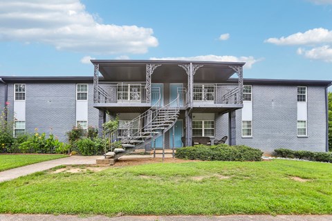 A blue building with a balcony and stairs leading to the entrance.