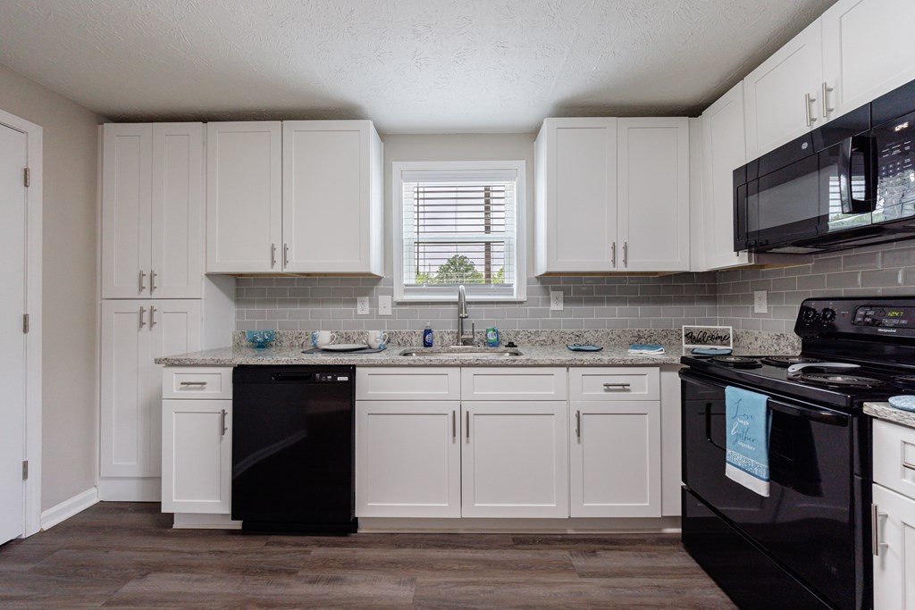 A kitchen with black appliances and white cabinets.