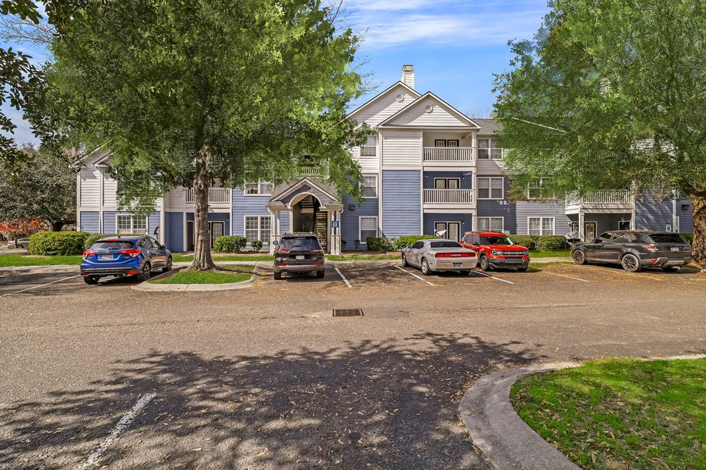 A blue car is parked in front of a two-story building.
