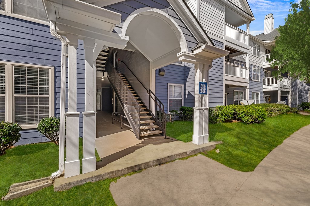 A blue building with a white porch and stairs leading up to it.