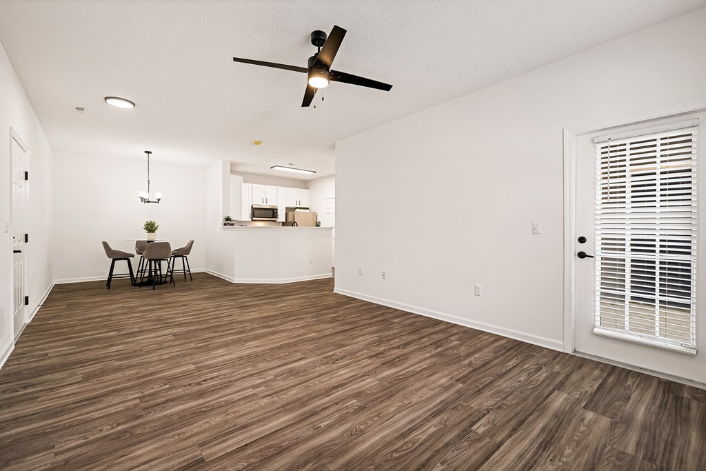 A room with a ceiling fan and wooden flooring.