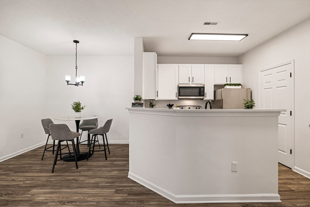 A kitchen with a white counter and a dining table with four chairs.