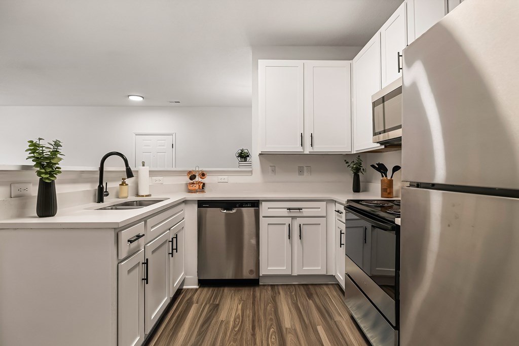 A modern kitchen with white cabinets and stainless steel appliances.