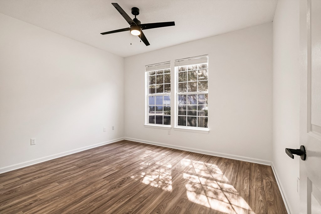 A room with a ceiling fan and a window with blinds.