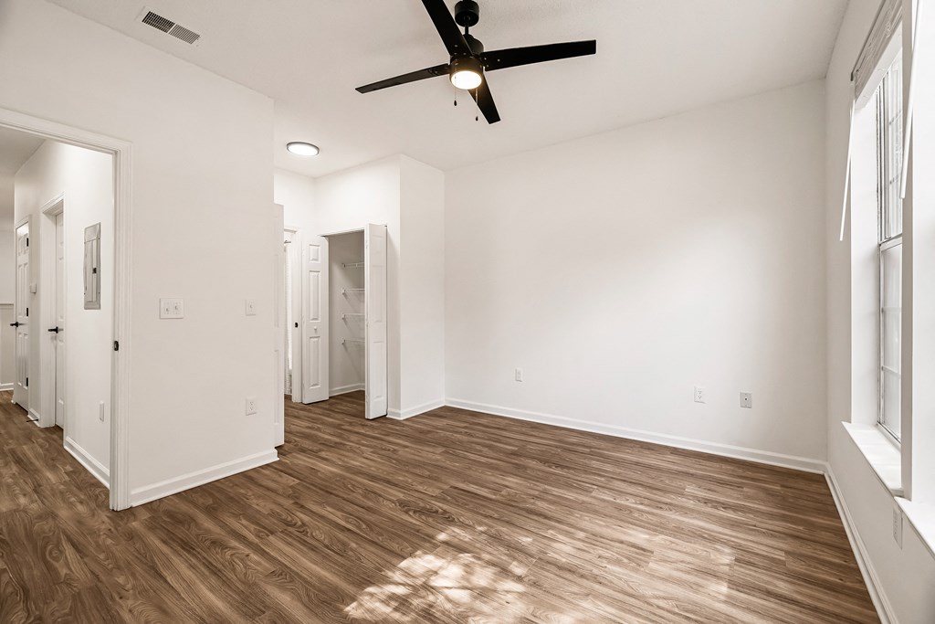 A room with a ceiling fan and wooden flooring.
