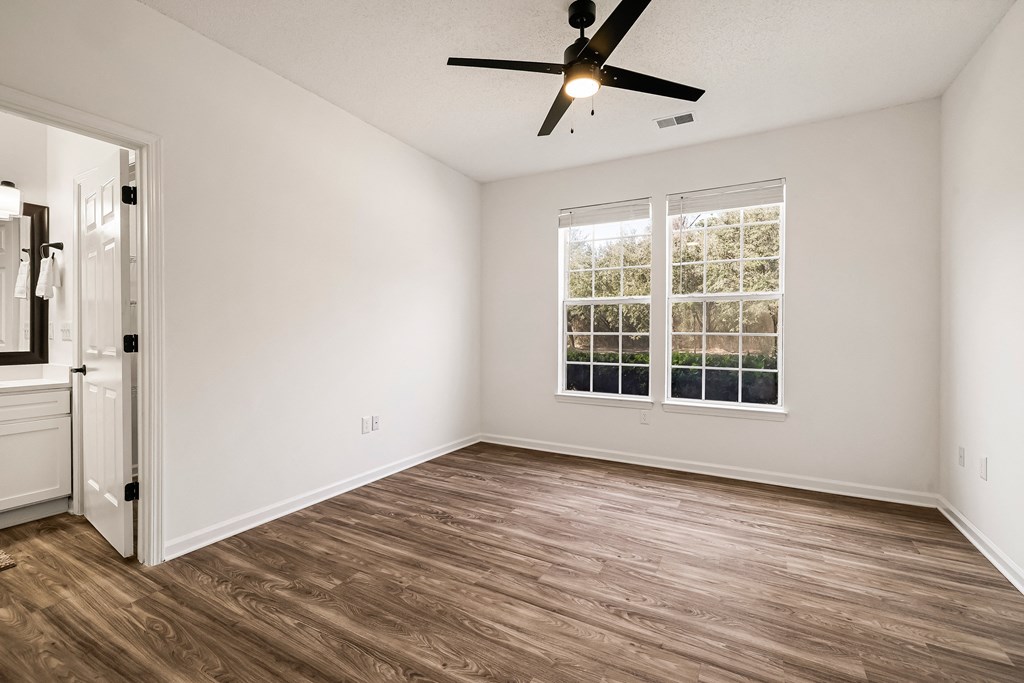 A room with a ceiling fan and a window with blinds.