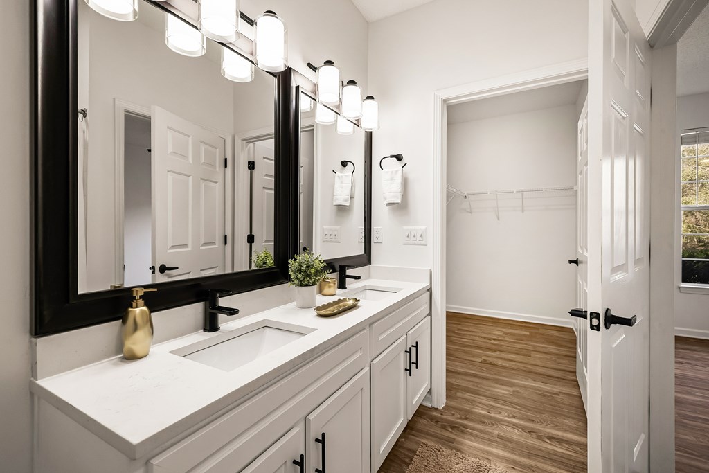 A bathroom with a vanity, a mirror, and lights.