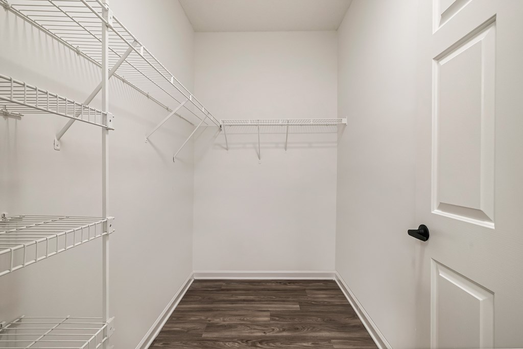 A white closet with a door and shelves.