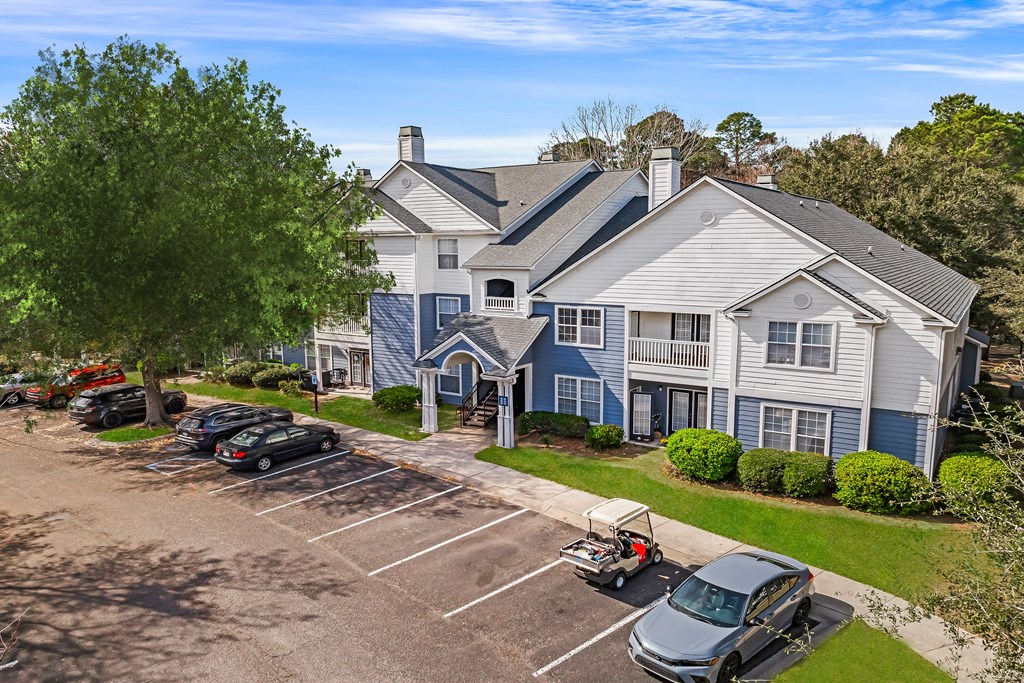 A large house with a parking lot in front.